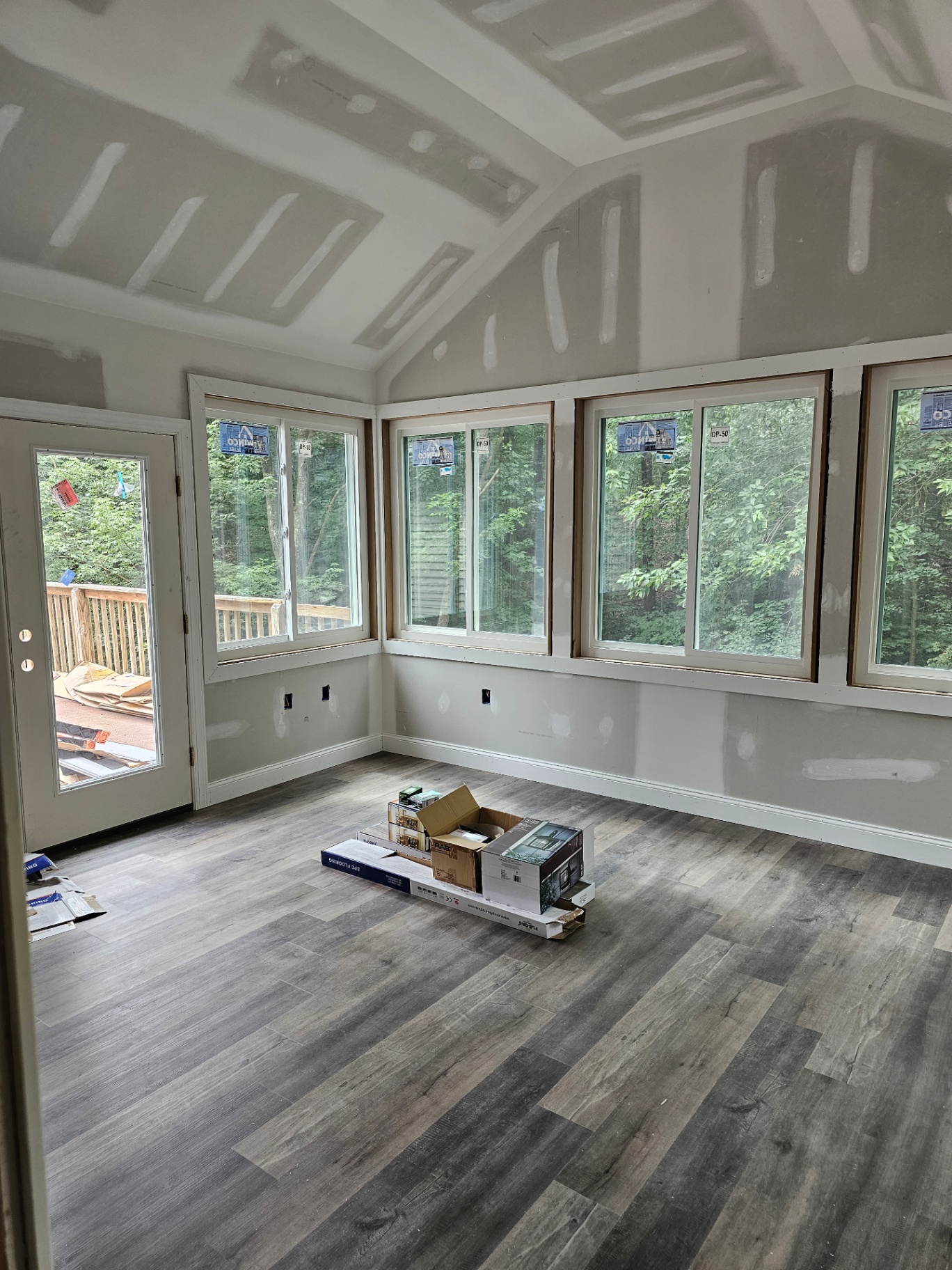 Interior of new sunroom addition with vaulted ceiling and wood-look flooring