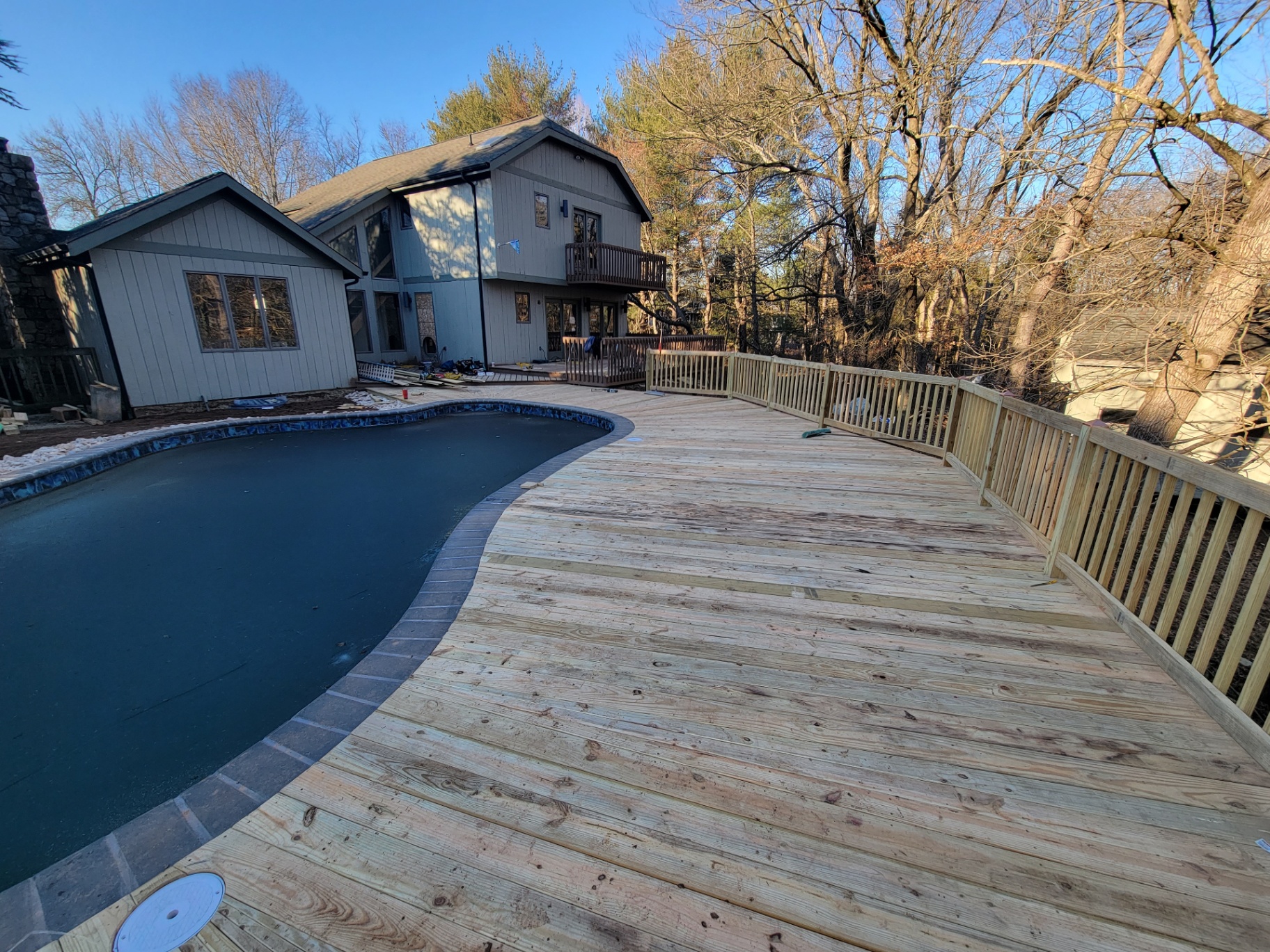 New pressure-treated deck alongside pool with view of the house