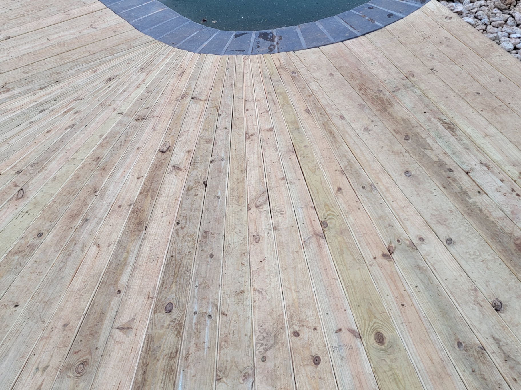 Close-up of radial deck boards meeting pool coping