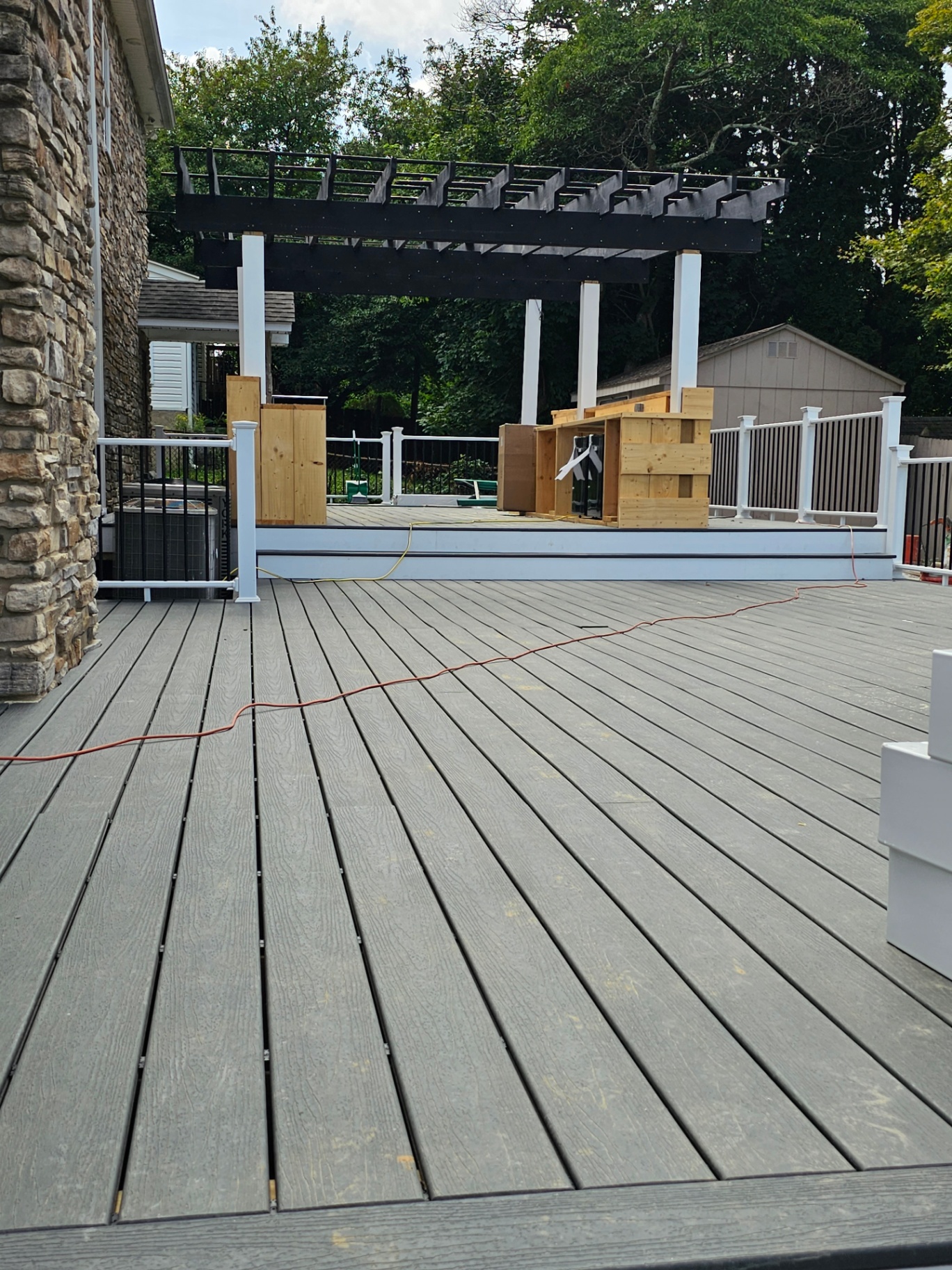 Expansive gray composite deck with black pergola and white railings