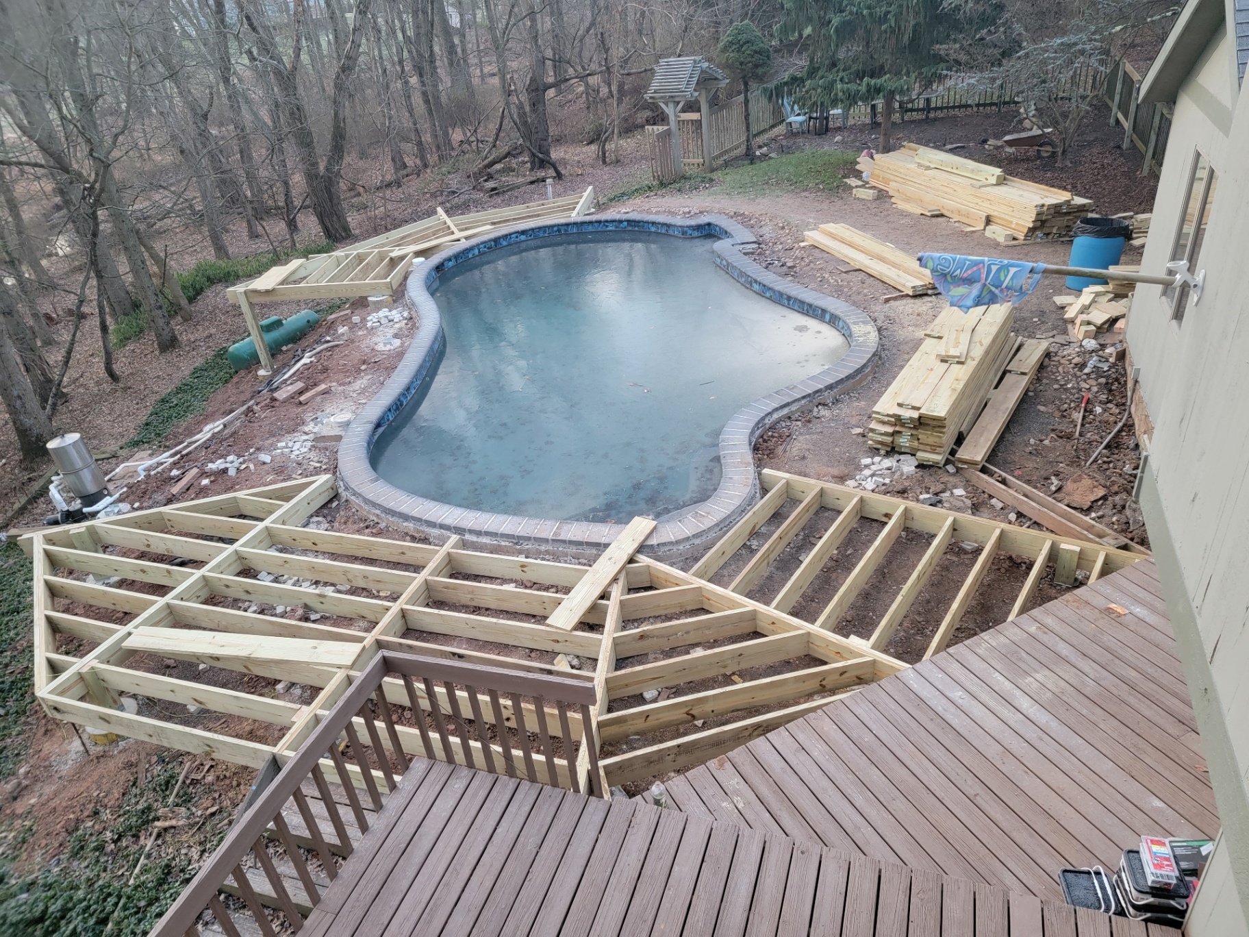 Deck framing in progress around a backyard pool