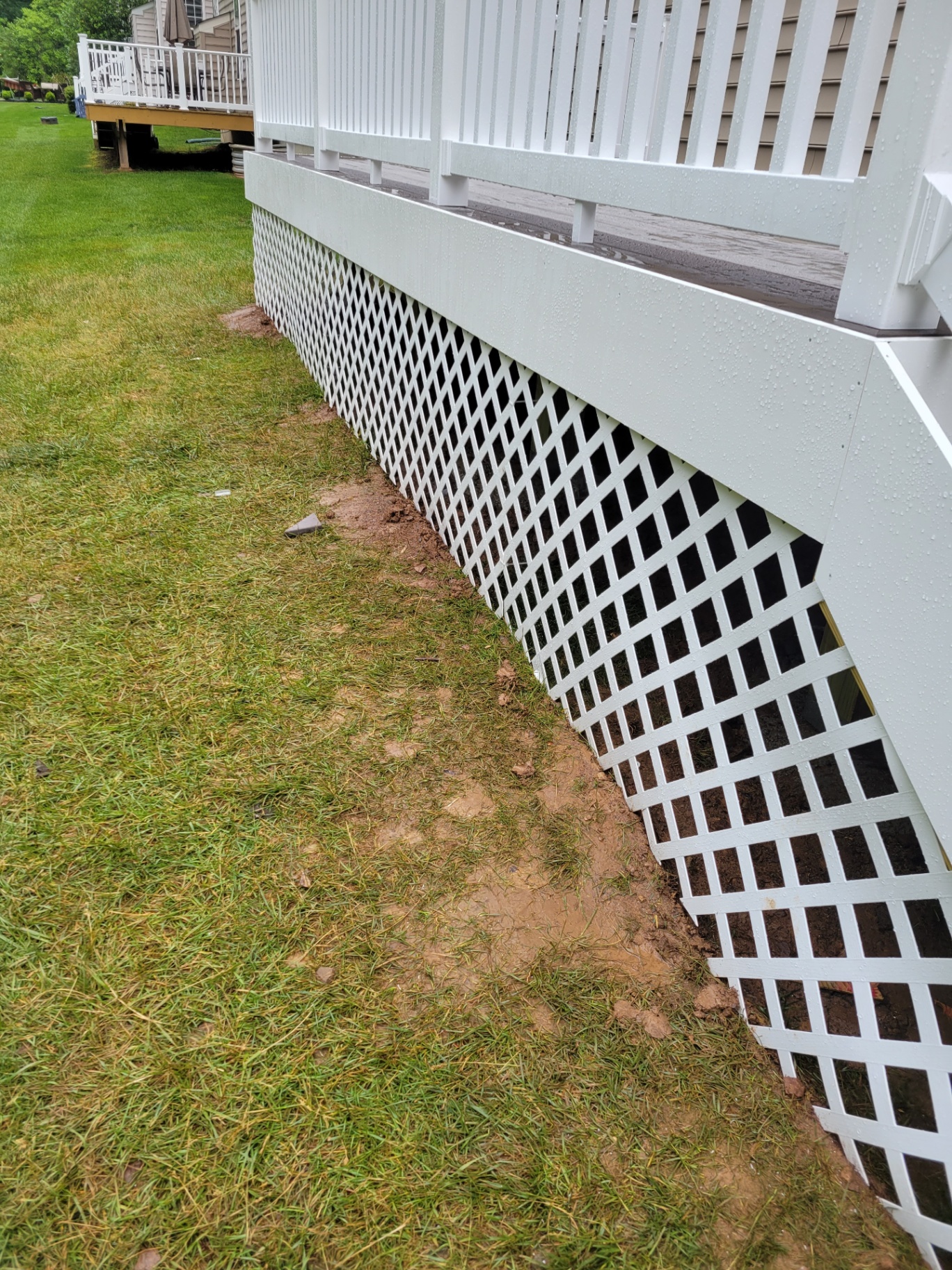 Close-up of white lattice deck skirting along a lawn